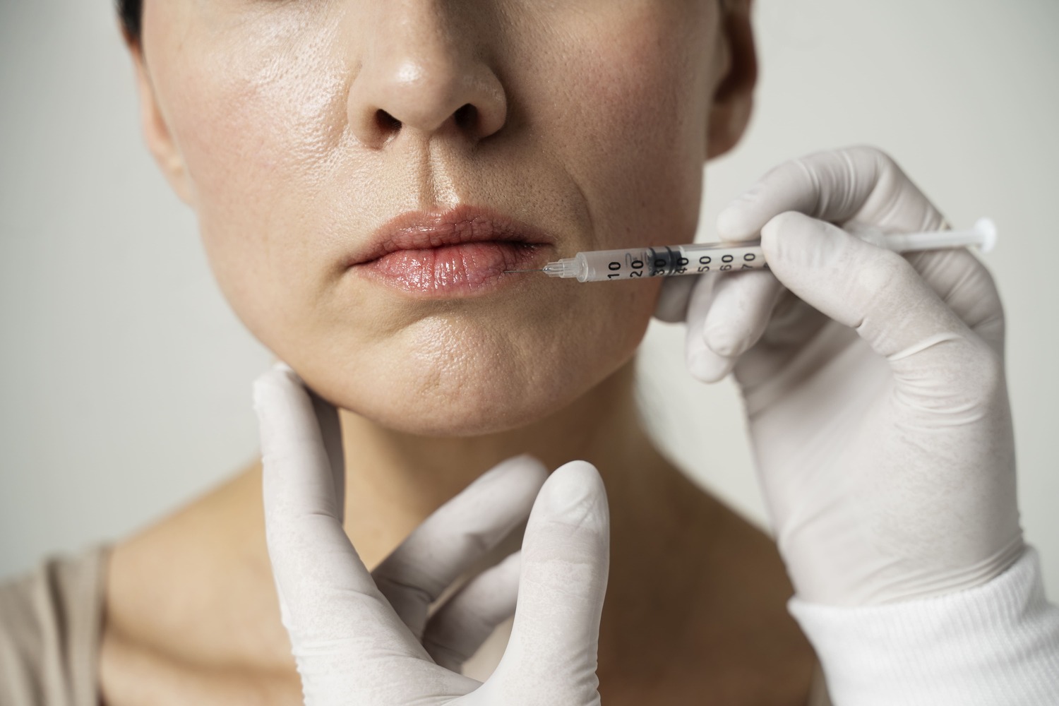 close up hand injecting woman_s lip_